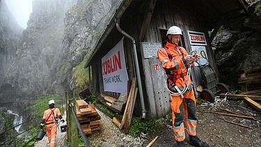 Foto von zwei Personen in Schutzuniform und Kletterausrüstung in einer Schlucht.    