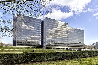 The picture shows an office building with a glass façade