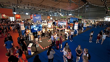 Foto einer Messehalle von innen mit vielen Personen an Messeständen