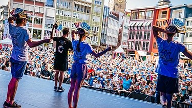 Foto von einer Bühne, wo vier Personen tanzen. 