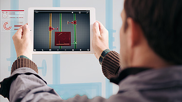 Foto von einer Person, die man von hinten sieht und ein Tablet in den Händen hoch hält