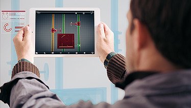 Foto von einer Person, die man von hinten sieht und ein Tablet in den Händen hoch hält