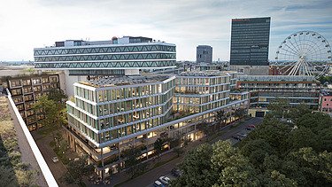 Das Bild zeigt ein Bürogebäude in einer Luftaufnahme, im Hintergrund weitere Gebäude und ein Riesenrad