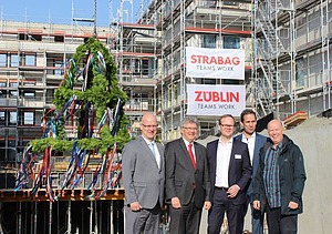 Foto von freundlich schauenden Männern auf einer Baustelle, beim hissen des Richtkranzes.  