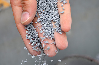 Foto einer Hand, die graue Kügelchen runter rieseln lässt