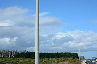 Foto eines Mastes mit einem technischen Gerät auf der Spitze, bei blauem Himmel