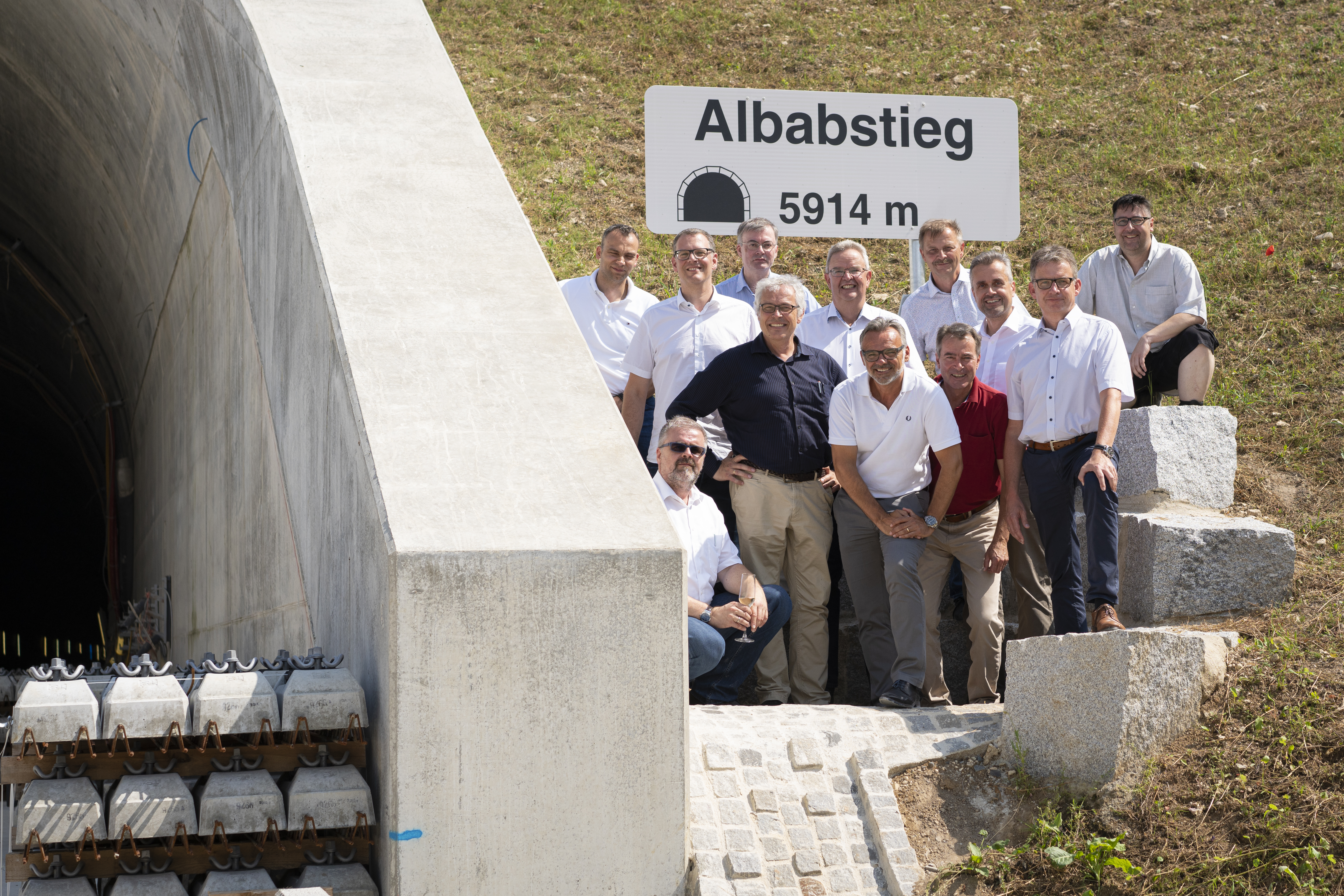 Foto von freundlich schauenden Männern, die neben einem Tunell stehen. 