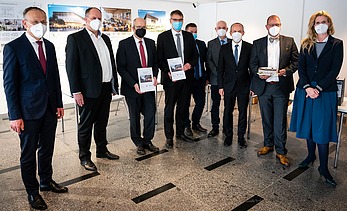 Foto von mehreren, stehenden Personen, die Coronamasken tragen