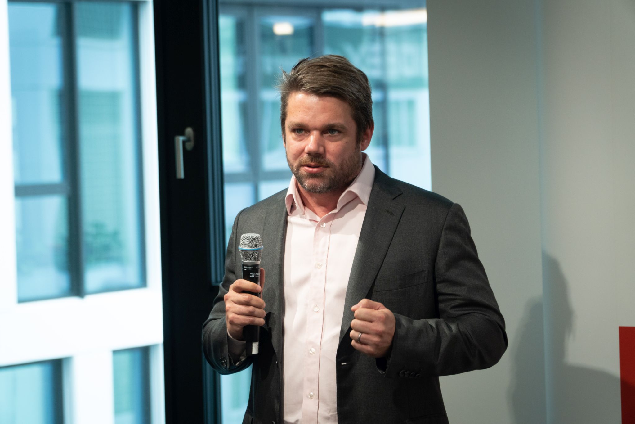 Foto von Klemens Haselsteiner im Anzug mit Microphon in der Hand. 