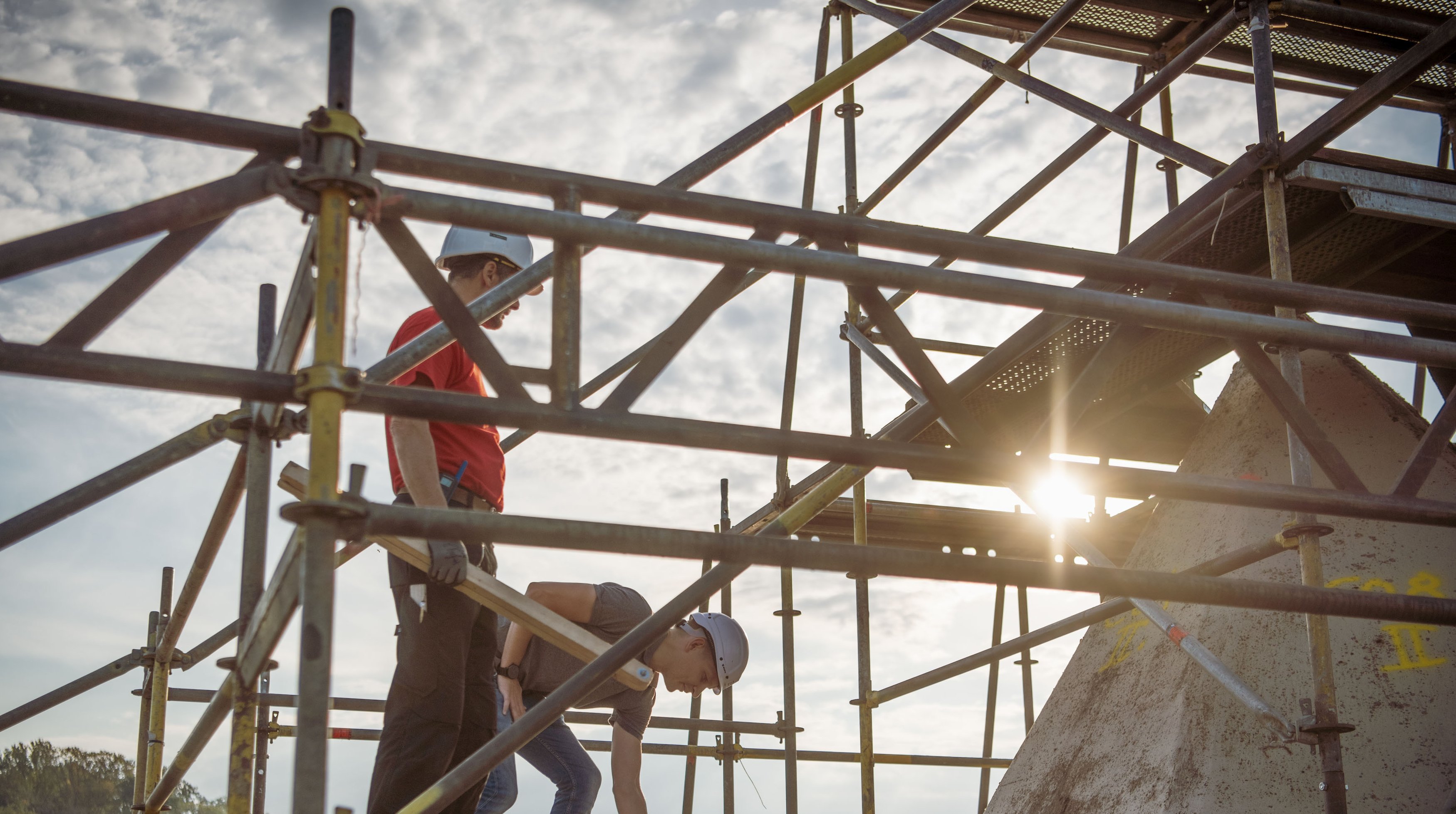  Foto von zwei Personen die auf einem Gerüst stehen.