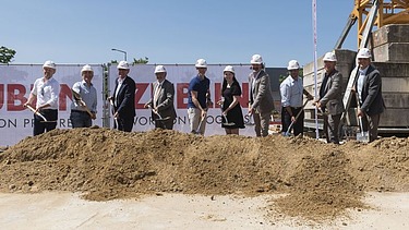 Photo of several people in suits at the laying of the foundation stone.