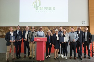 Foto von Preisträger:innen und Laudator:innen der BIM Preise Bayern 2023, im Hintergrund eine Bildschirmpräsentation