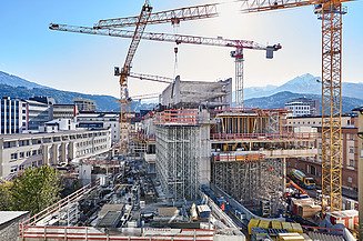 Foto von einer Baustelle eines Hochhaus umzingelt von mehreren Kränen