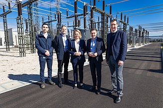 Foto von fünf Personen, die vor einem Umspannwerk stehen