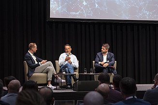Foto von drei sitzenden Personen bei einer Podiumsdiskussion