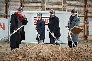Foto von vier Männern, die auf einer Baustelle, Erde mit einem Sparten schaufeln.