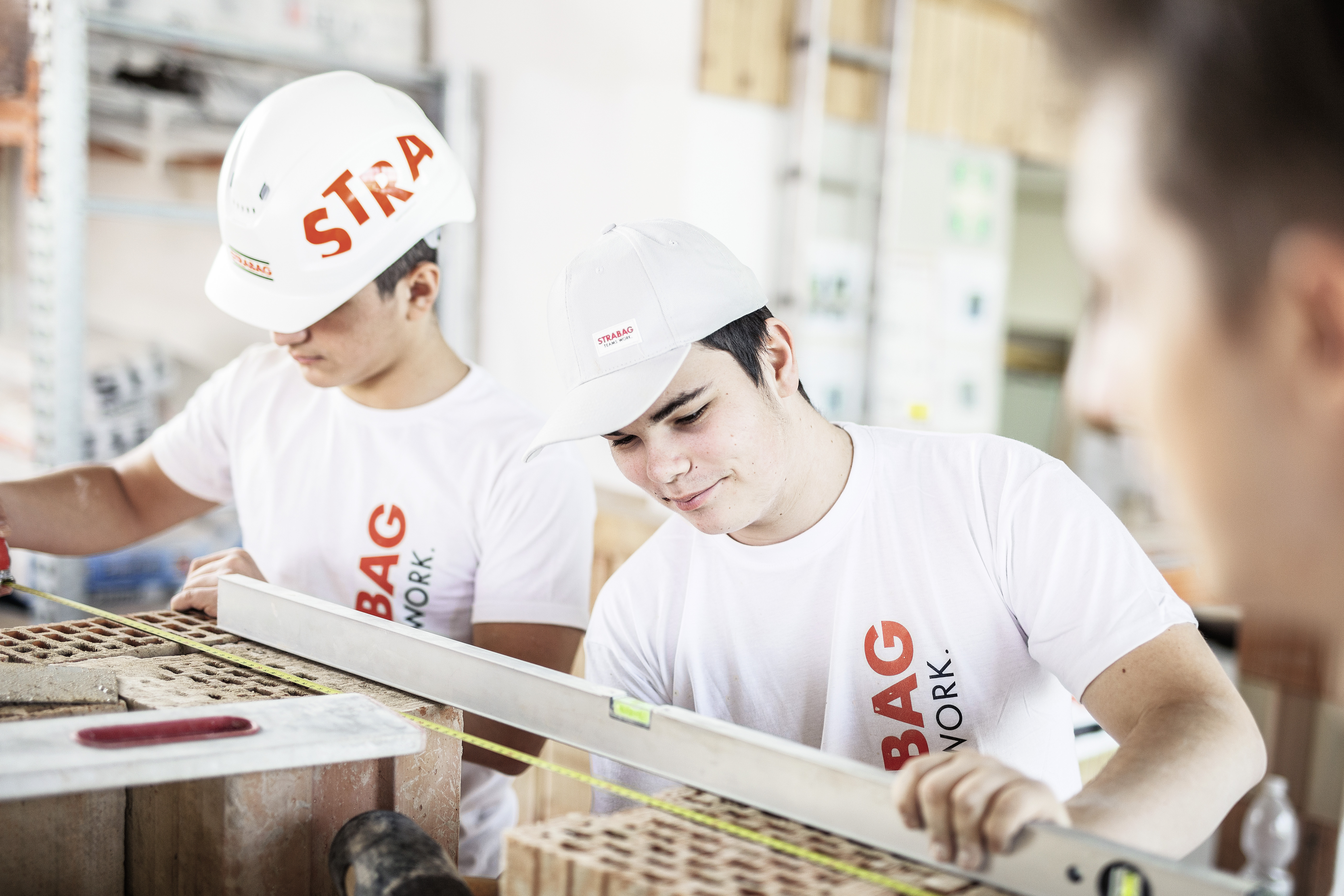 The photo shows two STRABAG apprentices in a work situation. 