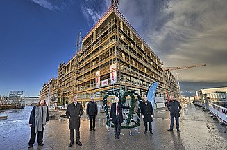 Foto von mehreren Personen die vorm Richtkranz stehen über dem LabCampus am Flughafen München.