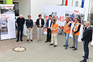 Foto von mehreren Personen, die vor einem Plakat stehen