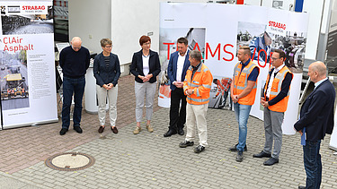 Foto von mehreren Personen, die vor einem Plakat stehen