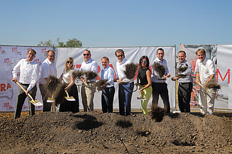 Foto von mehreren Personen mit Schaufeln in der Hand bei einem symbolischen Spatenstich