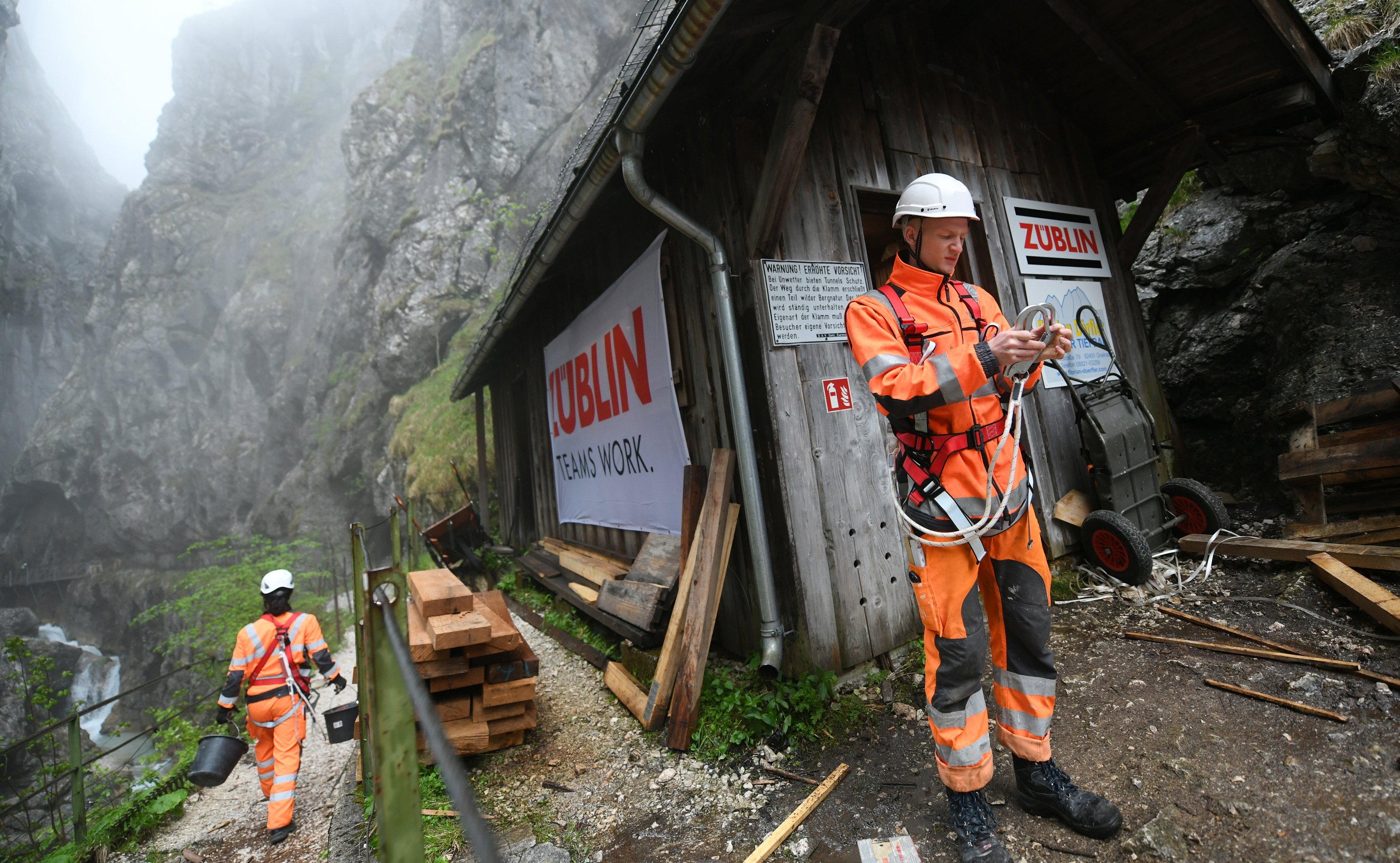 Foto von zwei Personen in Schutzuniform und Kletterausrüstung in einer Schlucht.    