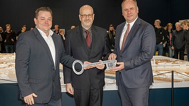 Image of three people holding a symbolic key