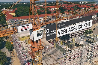 Foto von einem Kran auf einer Baustelle der ein Banner trägt.  