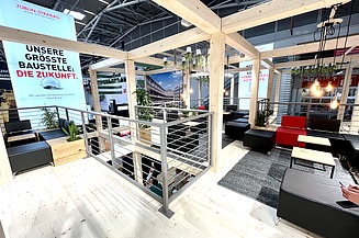 Foto von einem Messestand von STRABAG. Zu sehen ist eine Sitzecke.    