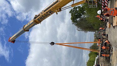 Foto von einer Baustelle mit mehren Personen in Schutzausrüstung. 