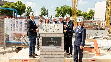 Foto von mehreren Personen, die freundlich schauen bei der Grundsteinlegung. 