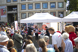 Foto von einem ZÜBLIN-Stand, wo eine Reportage von einem Roboter gedreht wird. Drumherum sind viele Personen versammelt    