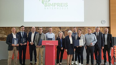 Foto von Preisträger:innen und Laudator:innen der BIM Preise Bayern 2023, im Hintergrund eine Bildschirmpräsentation