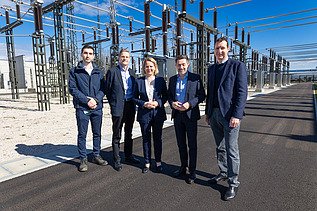 Foto von fünf Personen, die vor einem Umspannwerk stehen