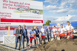 The photo shows several people with shovels behind a pile of earth