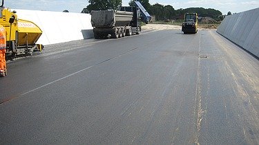 Das Bild zeigt eine Straße mit frischem Walzasphalt