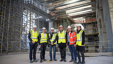 Foto von mehreren Personen mit Bauhelmen in einer Baustelle