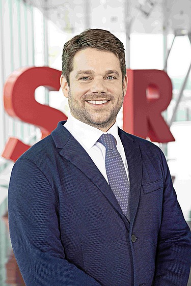 Photo of Klemens Haselsteiner standing in front of the red letters STRABAG