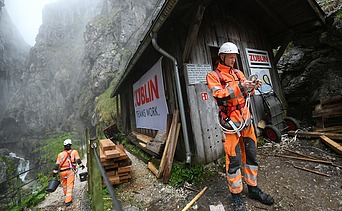 Foto von zwei Personen in Schutzuniform und Kletterausrüstung in einer Schlucht.    