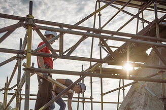  Foto von zwei Personen die auf einem Gerüst stehen.