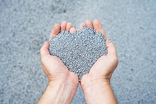 The picture shows two hands holding a pile of grey-blue balls