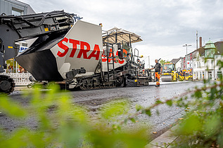 Foto einer großen Asphaltbaumaschine mit dem Schriftzug STRABAG auf der Seite