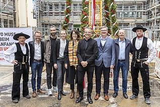 Foto von mehreren schick gekleideten Personen auf einer Baustelle.  