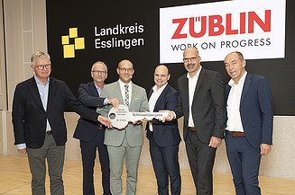 The picture 6 people in a row holding a large key