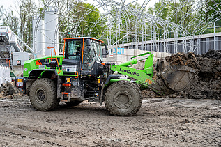 A large wheel loader transports soil in its bucket