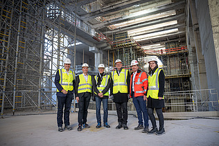 Foto von mehreren Personen mit Bauhelmen in einer Baustelle
