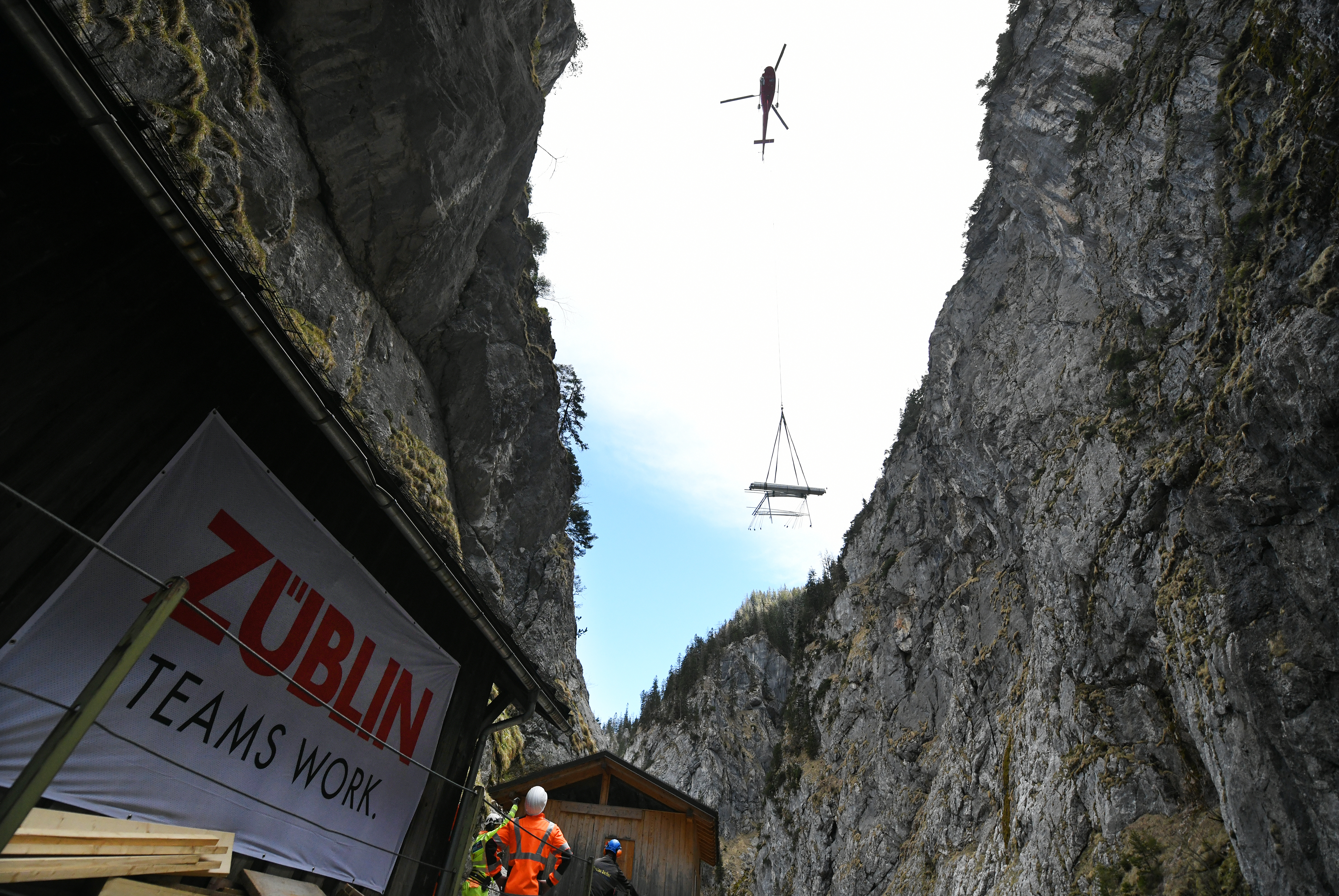 Foto von Hubschrauber, der Material in eine Schlucht abseilt.                 