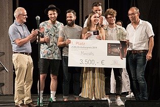 Foto von freudig Schauenden Personen auf einer Bühne, die den 1. Platz des ZÜBLIN-Kulturpreis 2019 in der Hand halten.  