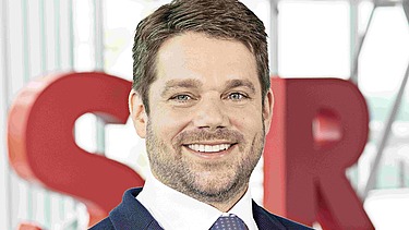 Photo of Klemens Haselsteiner standing in front of the red letters STRABAG