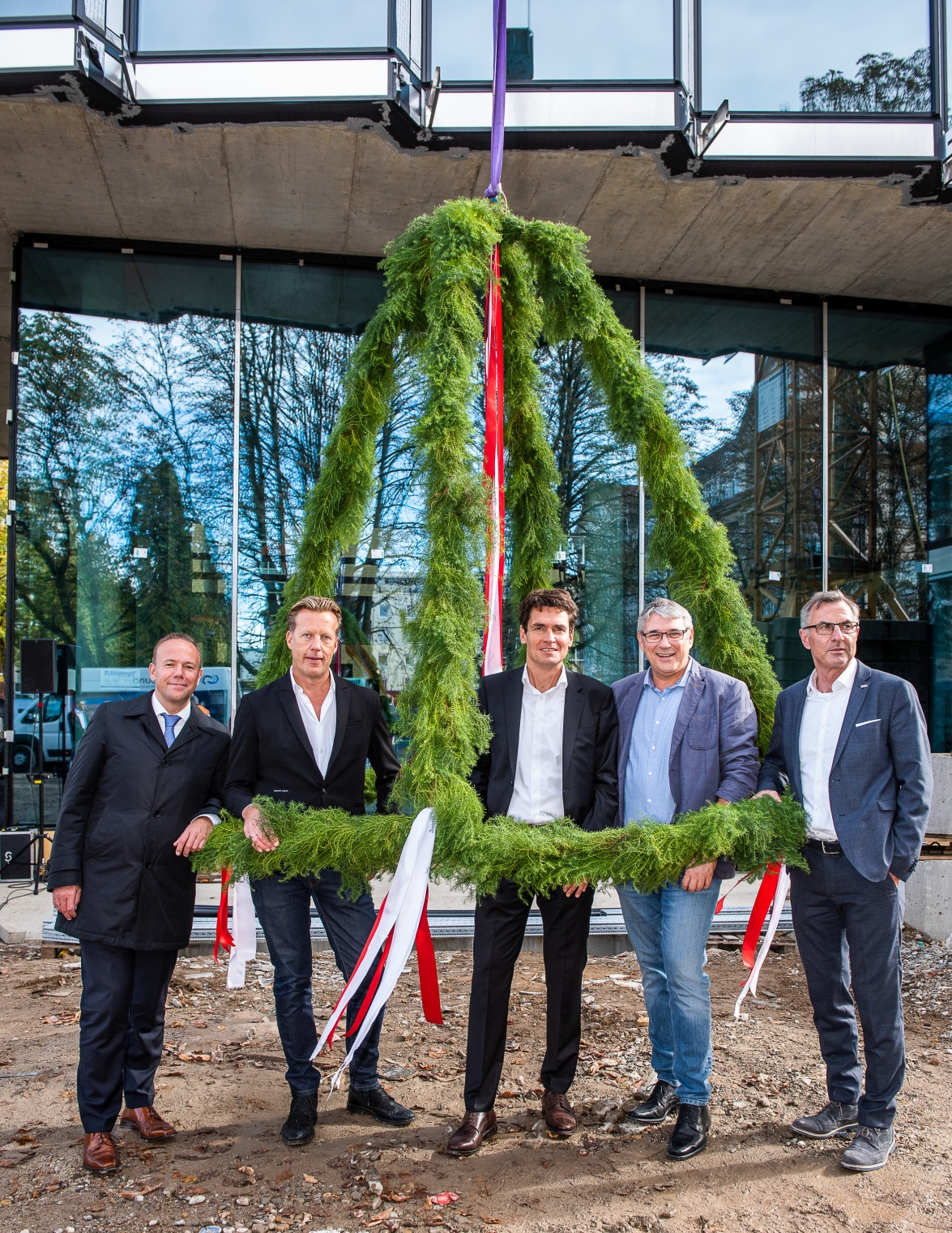 Foto von freundlich schauenden Männern, die unter dem Richtkranzkranz stehen. 